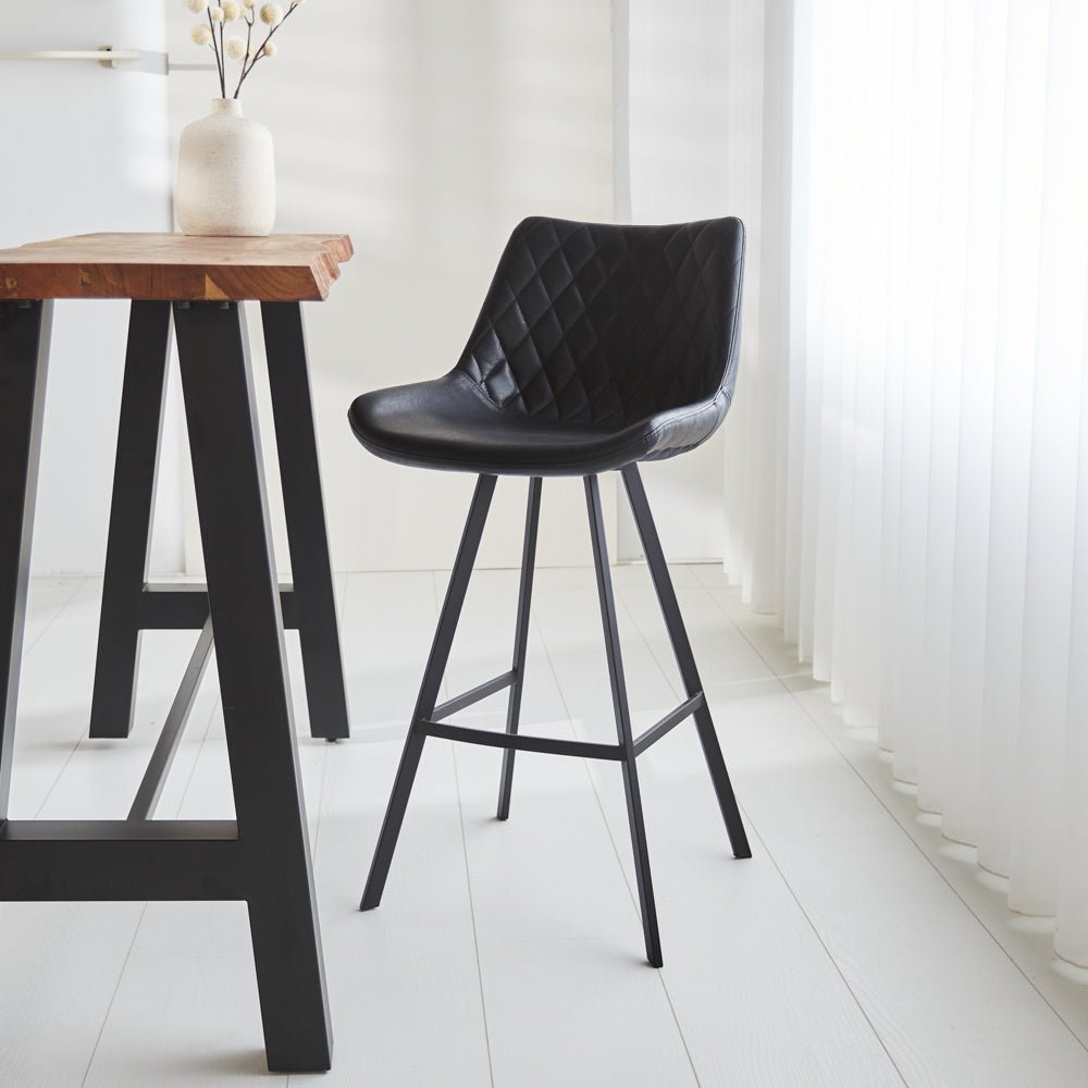 Barhocker Juno Dimehouse Schwarz LxBxH 86x56x56 Kunstleder Stimmungsvolles Foto diagonal von vorne